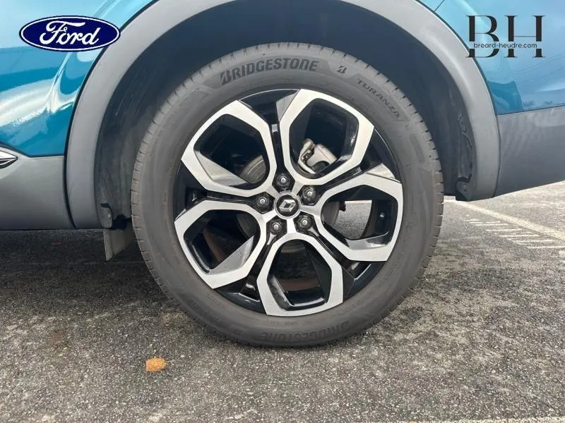 Gros plan sur la roue avant droite du Renault Arkana bleu Zanzibar, jante alu au design moderne et pneu Bridgestone.