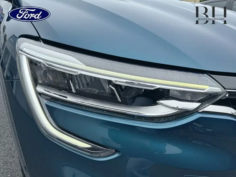 Gros plan sur le phare avant gauche du Renault Arkana bleu Zanzibar mettant en valeur ses LED distinctives.