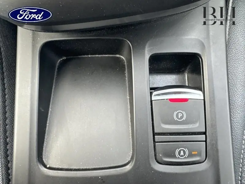 Gros plan sur la console centrale noire du Renault Arkana Bleu Zanzibar, avec les commandes de frein à main électronique et auto-hold.