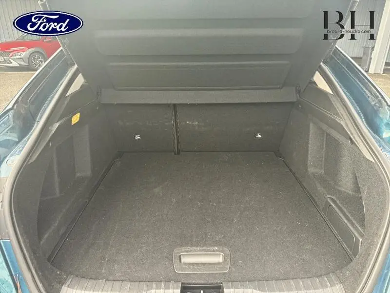 Coffre ouvert du Renault Arkana bleu Zanzibar, vue arrière montrant un espace de chargement vide et propre.