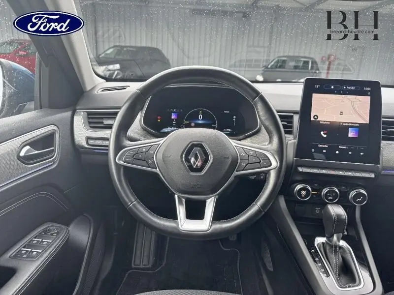 Vue intérieure centrée sur le volant cuir multifonction et l'écran tactile du Renault Arkana Bleu Zanzibar 2022.