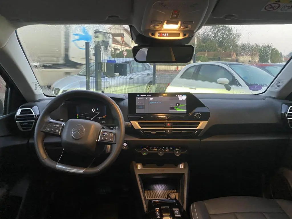 Vue intérieure avant de la Citroën C4 gris foncé 2025, avec tableau de bord digital et écran tactile central allumé.