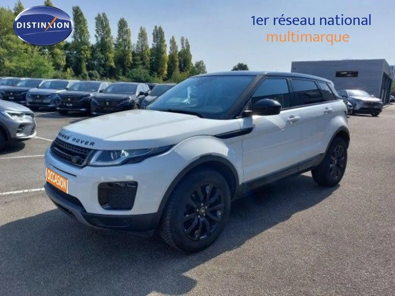 Vue 3/4 avant d'un Range Rover Evoque blanc 2018 avec détails noirs, garé sur un parking extérieur multimarque.
