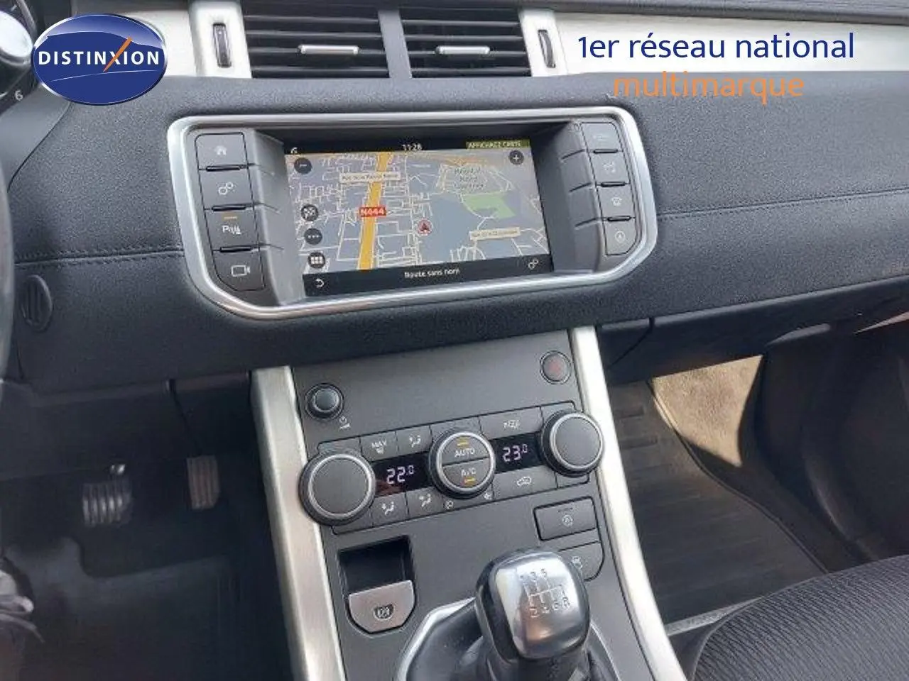 Vue rapprochée de la console centrale du Range Rover Evoque blanc 2018, avec écran tactile et levier de vitesses manuel.