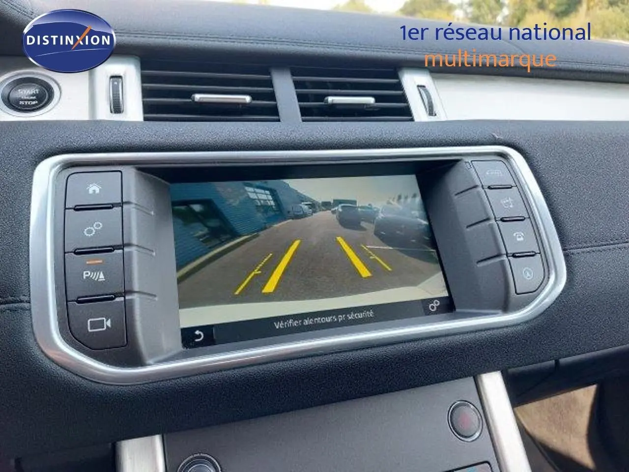 Écran central du tableau de bord du Range Rover Evoque blanc 2018 montrant la caméra de recul avec lignes de guidage jaunes.