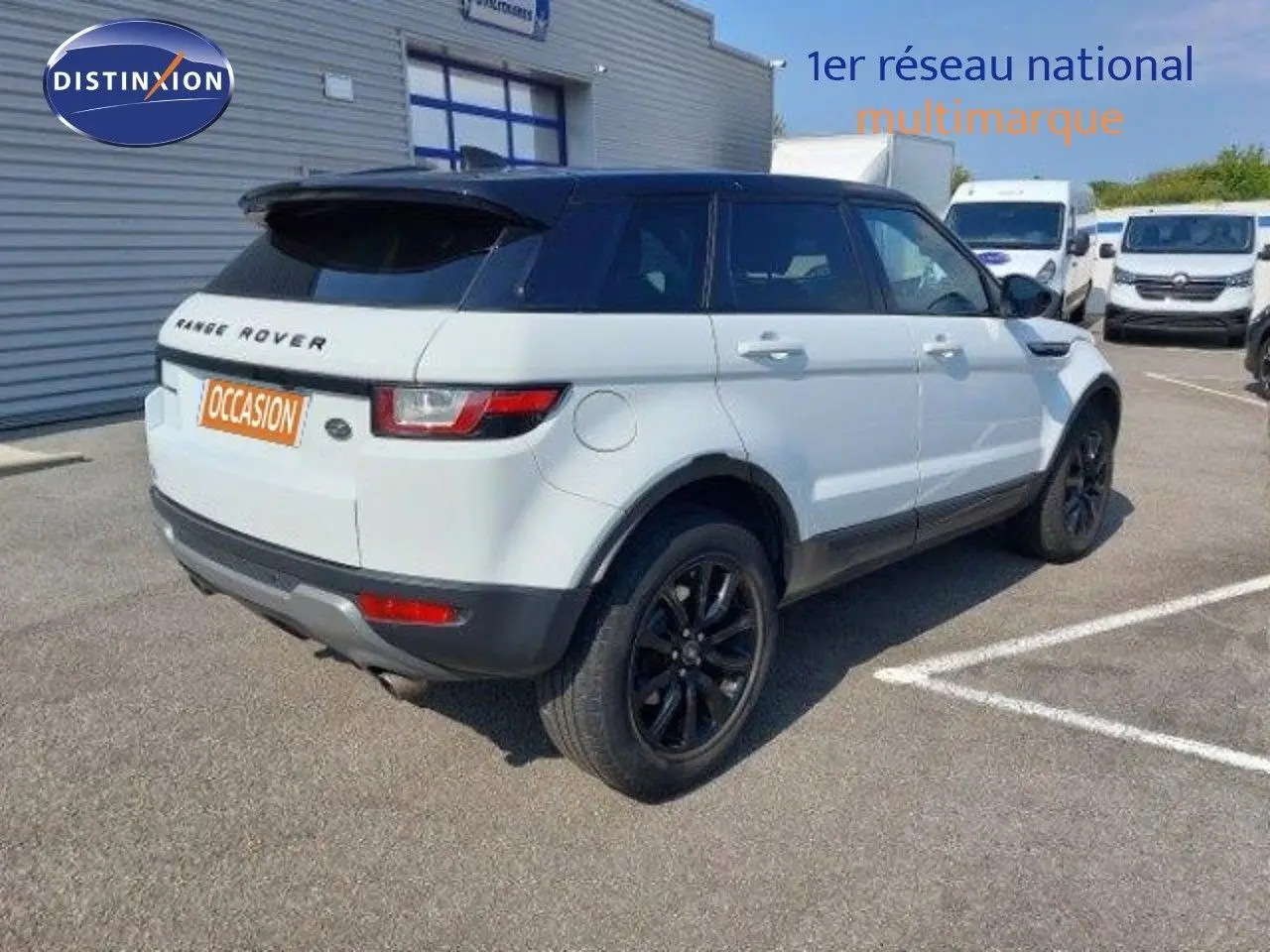Vue 3/4 arrière droite d'un Range Rover Evoque blanc de 2018 avec jantes noires et toit noir contrasté.
