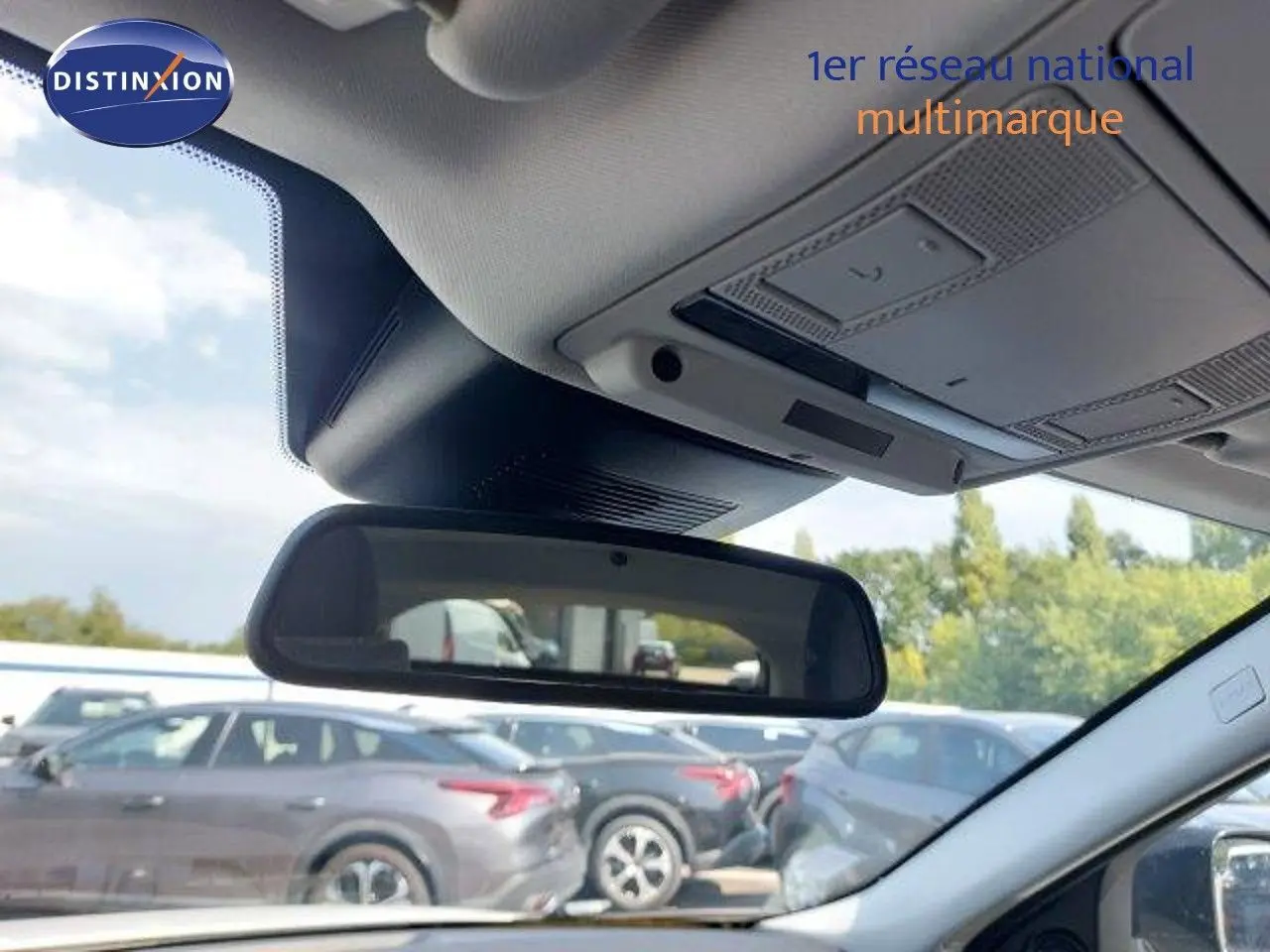 Vue intérieure du rétroviseur central du Range Rover Evoque blanc 2018, avec aperçu du ciel et véhicules en arrière-plan.