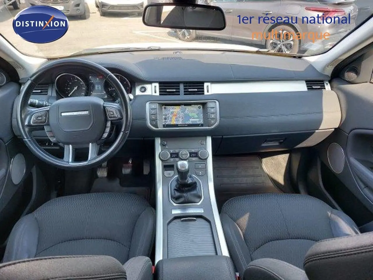 Intérieur du Range Rover Evoque 2018 en vue avant, tableau de bord noir avec écran tactile et boîte manuelle.