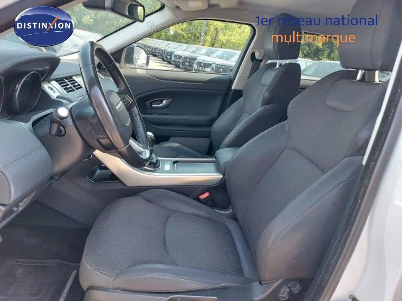 Intérieur du Range Rover Evoque blanc 2018, vue côté conducteur, sièges noirs et tableau de bord moderne.