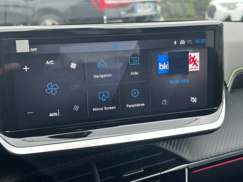 Écran tactile central du tableau de bord du Peugeot 208 Hybrid 2025 affichant les options de navigation et climatisation.
