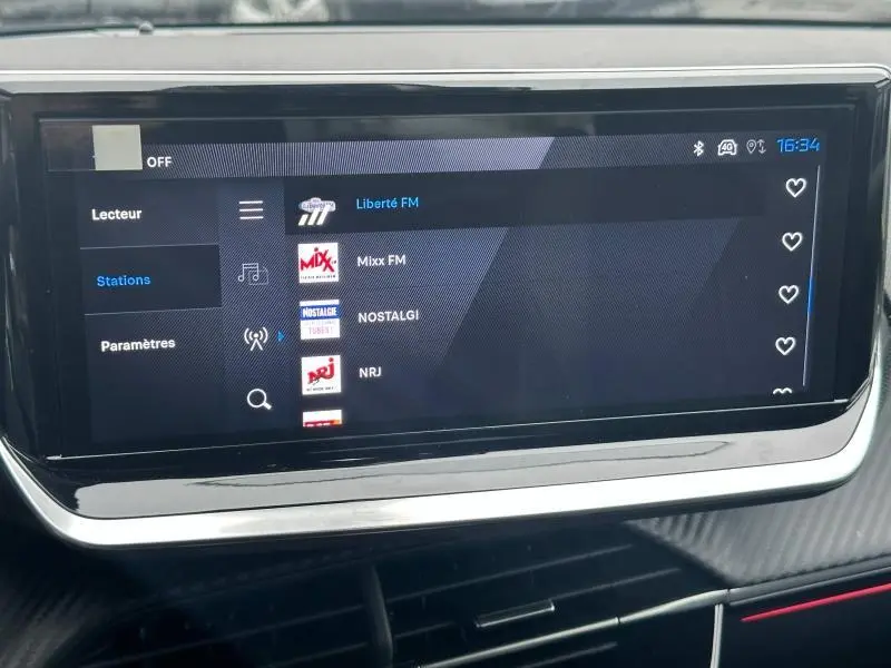 Écran tactile central de la Peugeot 208 Hybrid 2025 affichant la liste des stations radio avec interface moderne.