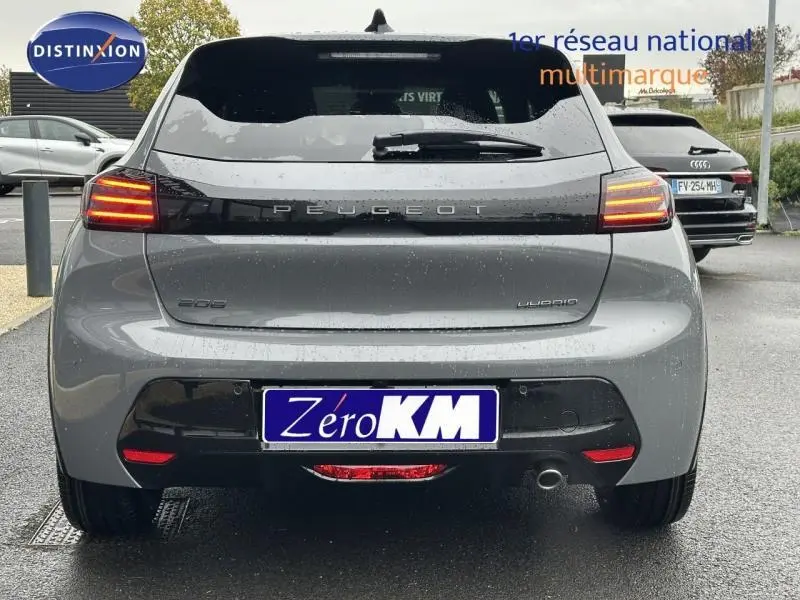 Vue arrière d'une Peugeot 208 grise 1.2 Hybrid 110ch GT avec feux allumés sous la pluie.