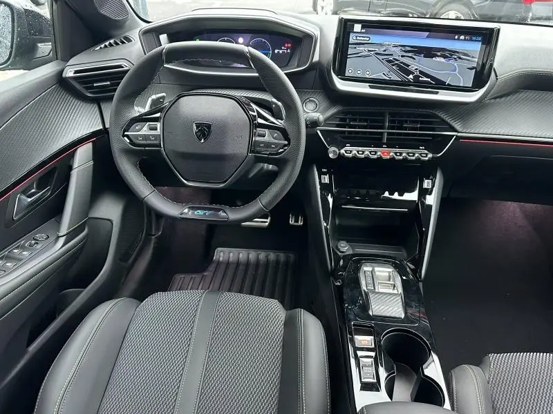 Intérieur de la Peugeot 208 Hybrid 1.2 GT 2025 vu de face, tableau de bord noir avec écran tactile et volant compact.