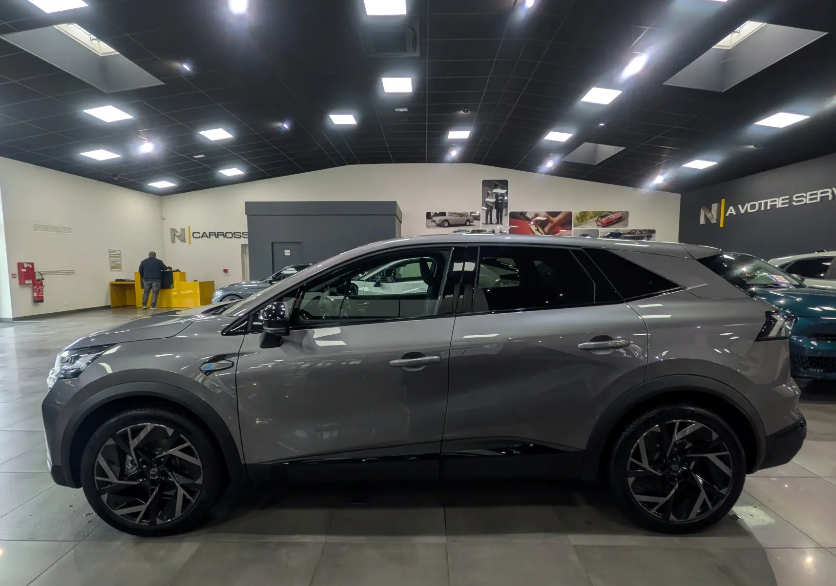 Profil côté gauche du Renault SYMBIOZ gris Cassiopé, version E-Tech full hybrid 160 ch Esprit Alpine, en showroom lumineux.