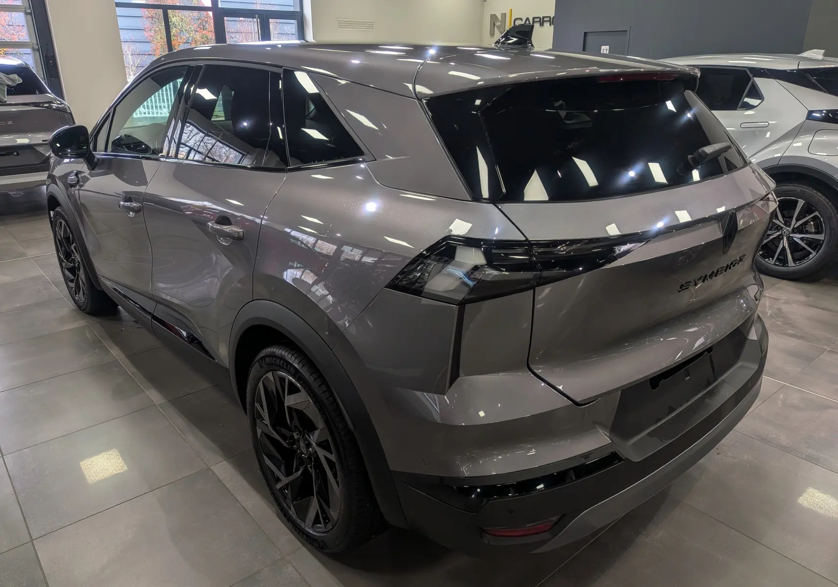 Vue 3/4 arrière droite du Renault SYMBIOZ gris Cassiopé avec feux arrière noirs et jantes noires en showroom.