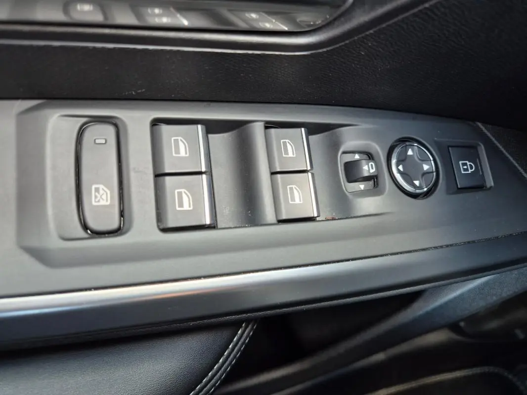 Vue rapprochée des commandes de lève-vitres et réglage des rétroviseurs côté conducteur du Peugeot 3008 gris clair 2024.