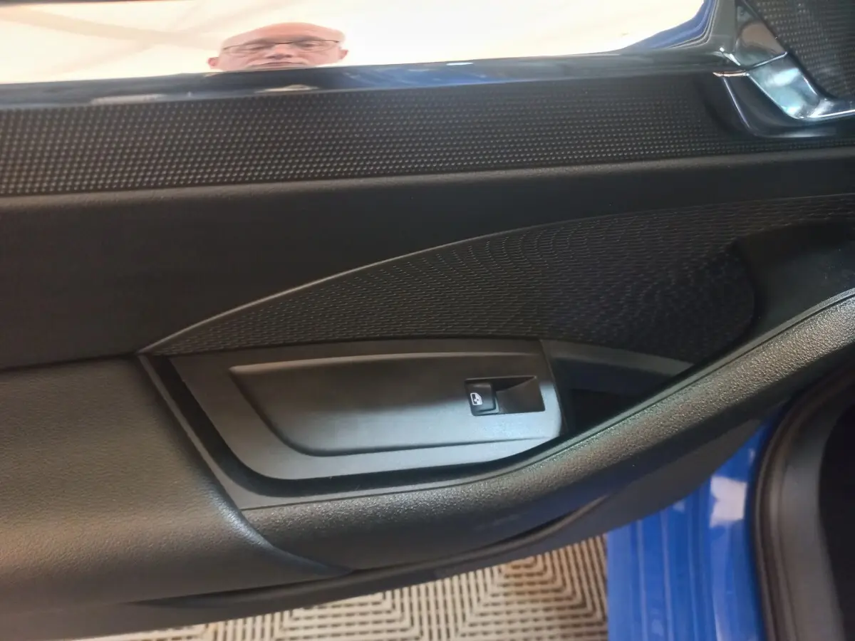 Intérieur côté conducteur de la porte d’une Skoda Octavia bleu 2022, avec commande de lève-vitre noir.