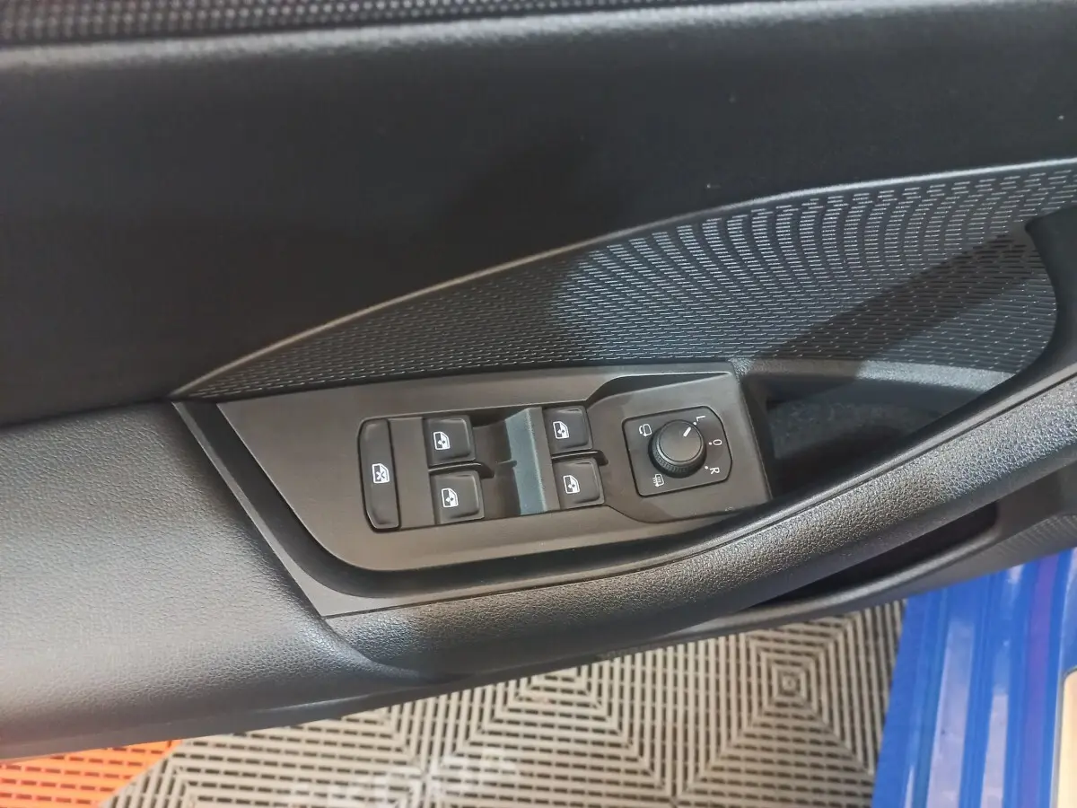 Gros plan sur les commandes électriques des vitres et rétroviseurs côté conducteur d’une Skoda Octavia bleu 2022.