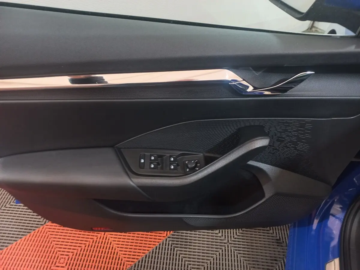 Vue intérieure côté gauche de la porte avant d’une Skoda Octavia bleue avec commandes électriques et garniture noire.
