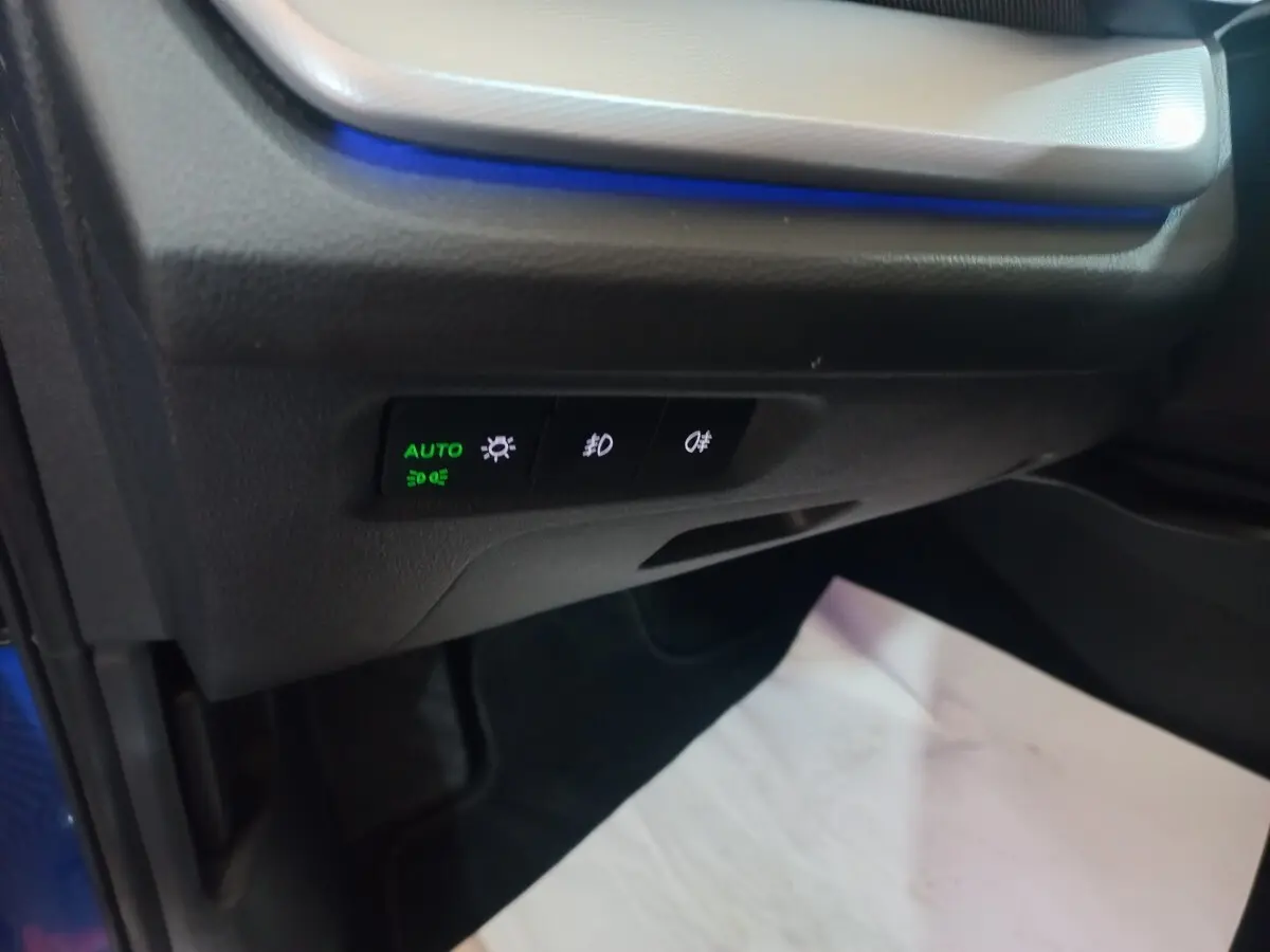 Détail des commandes d'éclairage avec rétroéclairage bleu à gauche côté conducteur d'une Skoda Octavia bleue 2022.