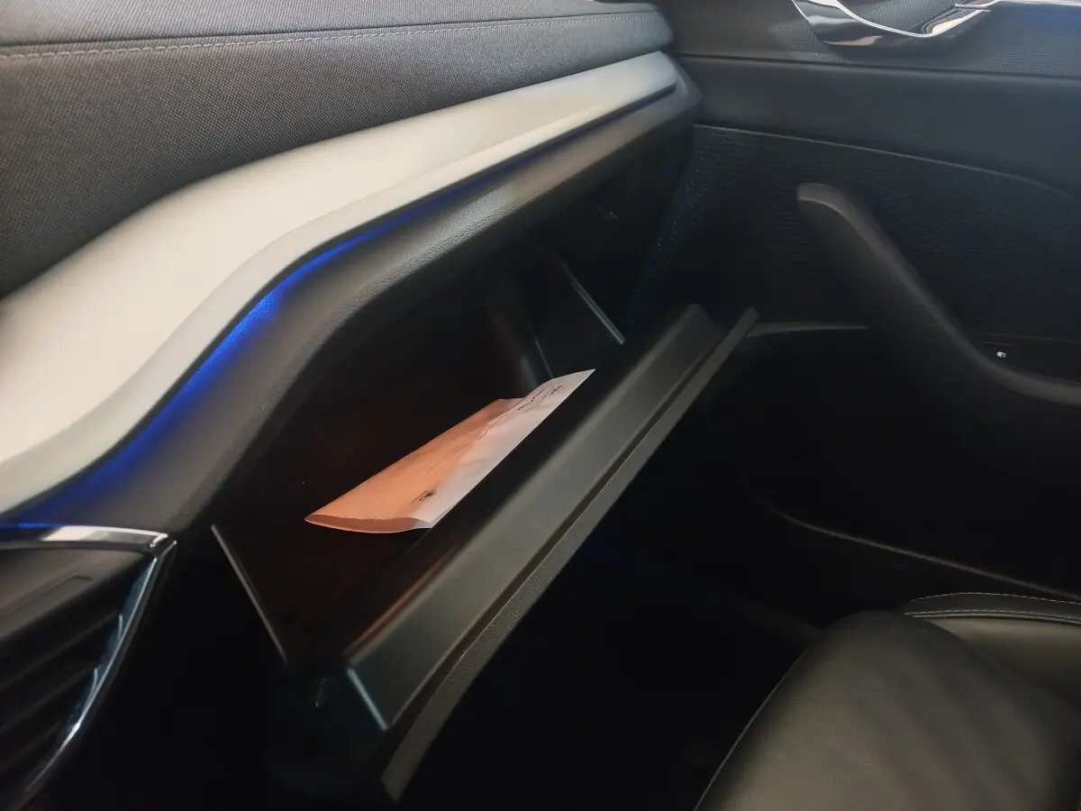 Intérieur de la Skoda Octavia 2022, vue côté passager sur la boîte à gants ouverte avec éclairage d’ambiance bleu.