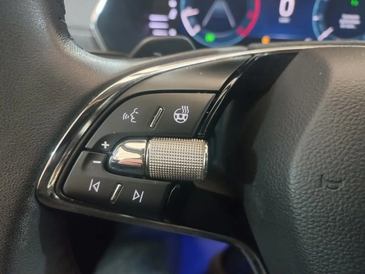 Gros plan sur les commandes gauche du volant cuir noir de la Skoda Octavia 2022 avec molette métallique et boutons tactiles.