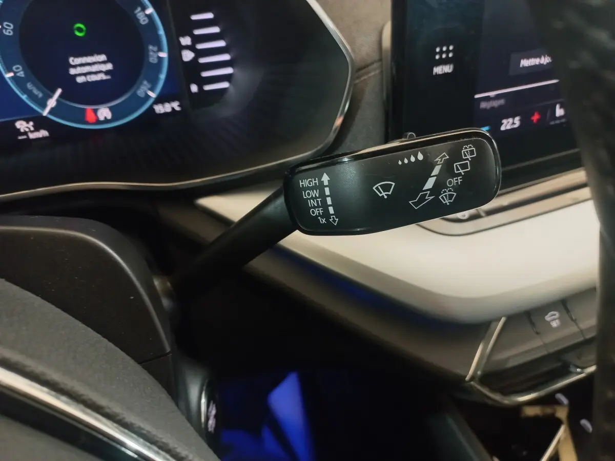 Gros plan sur la commande d’essuie-glace à gauche du volant dans l’habitacle clair de la Skoda Octavia bleue 2022.