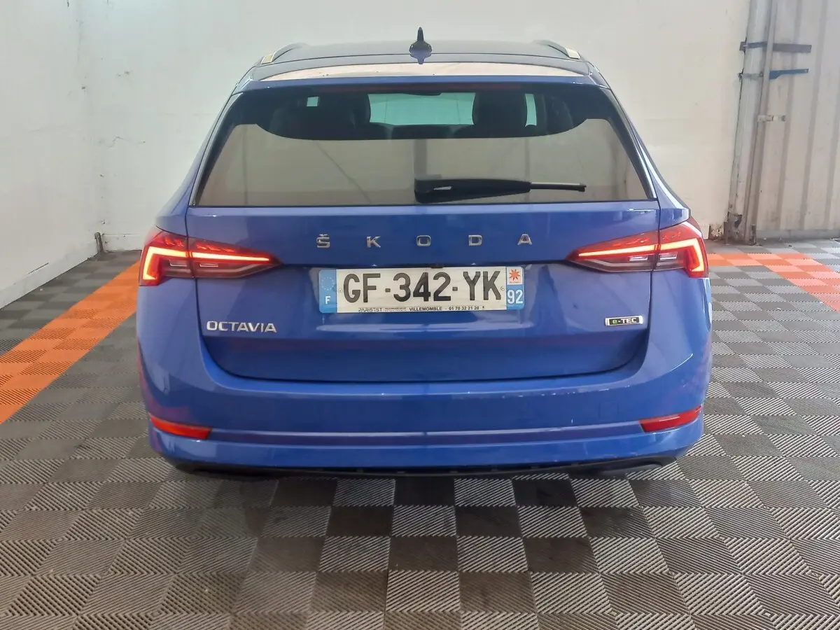 Vue arrière d'une Skoda Octavia bleu électrique avec feux LED allumés et badge e-TEC visible sur un sol à damier.