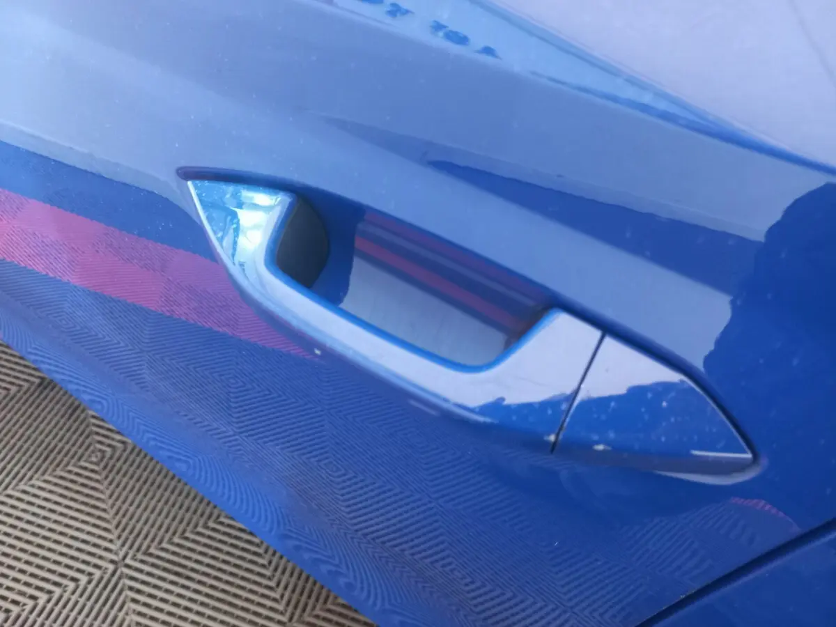 Poignée de porte côté gauche bleu brillant d'une Skoda Octavia 1.5 TSI mHEV e-TEC 2022, vue rapprochée.