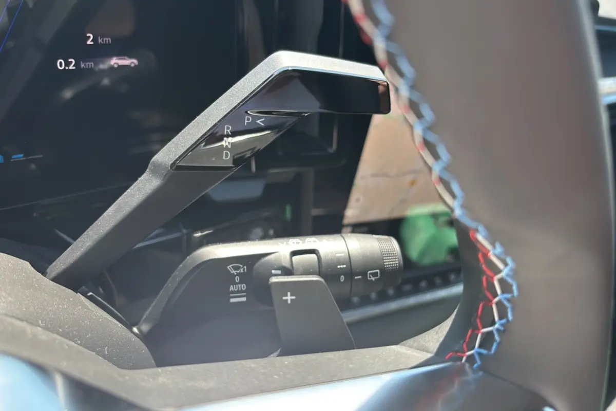 Gros plan sur la commande de boîte automatique et palettes au volant avec surpiqûres tricolores du Renault Austral E-Tech 200 Esprit Alpine.