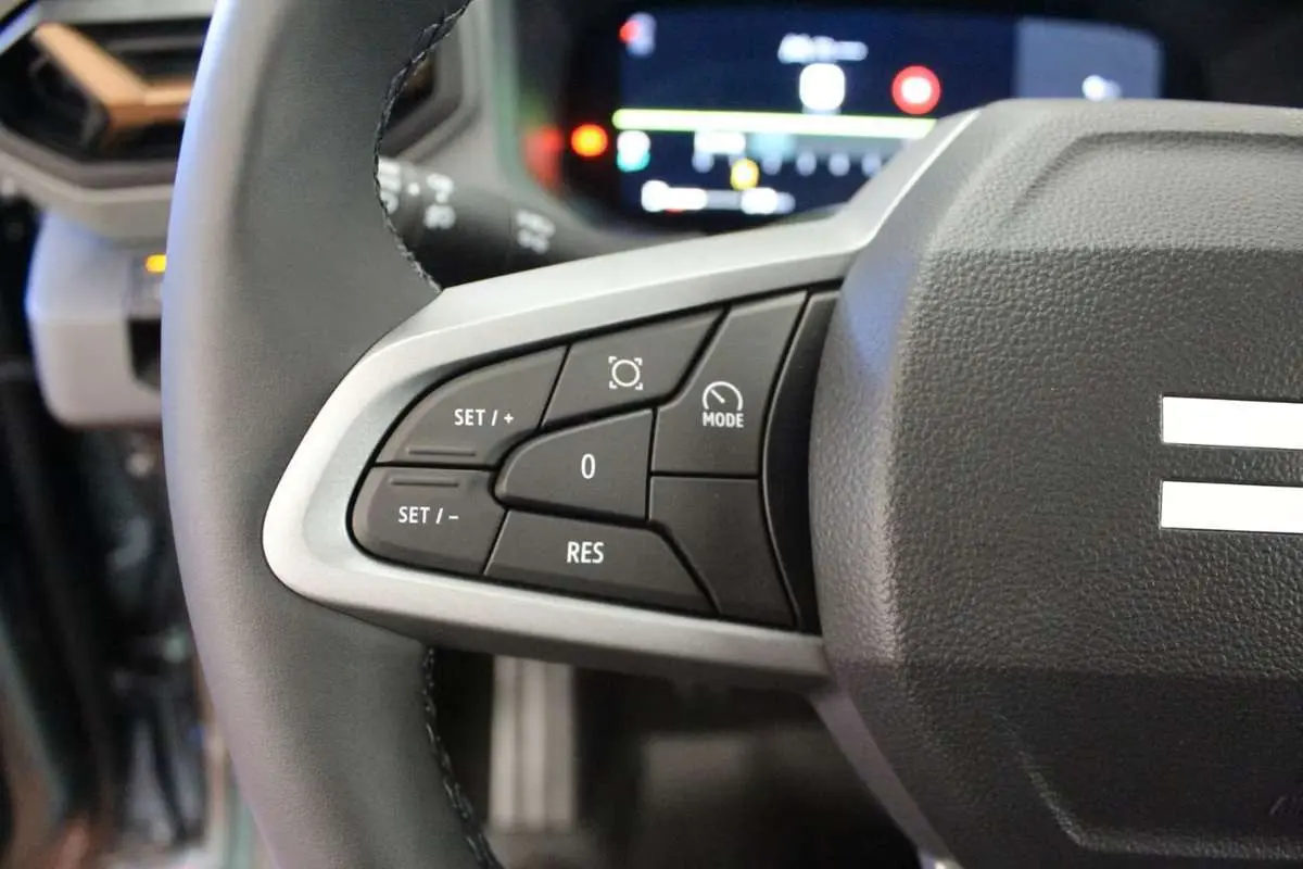 Gros plan sur le volant cuir du Dacia Bigster gris schiste, avec commandes de régulateur de vitesse visibles.