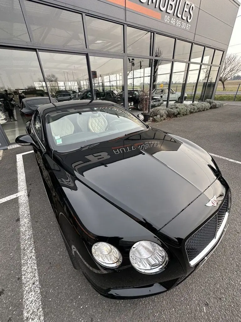 Bentley Continental GT Mulliner noire vue en 3/4 avant droit, mettant en valeur ses phares ronds et la calandre distinctive.