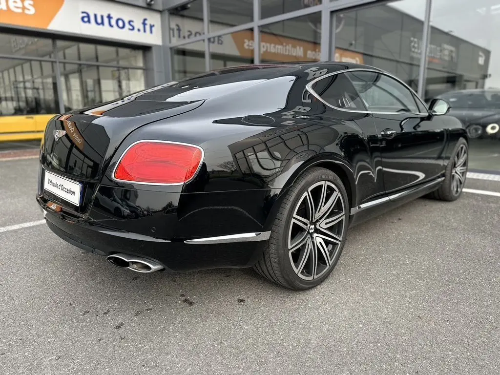 Bentley Continental GT 4.0 V8 Mulliner noire vue 3/4 arrière droit, avec jantes alliage distinctives et feux rouges.