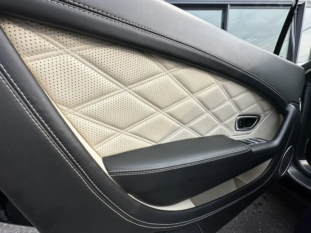 Détail de la porte côté gauche en cuir noir et beige matelassé du Bentley Continental GT 4.0 V8 Mulliner 2013.
