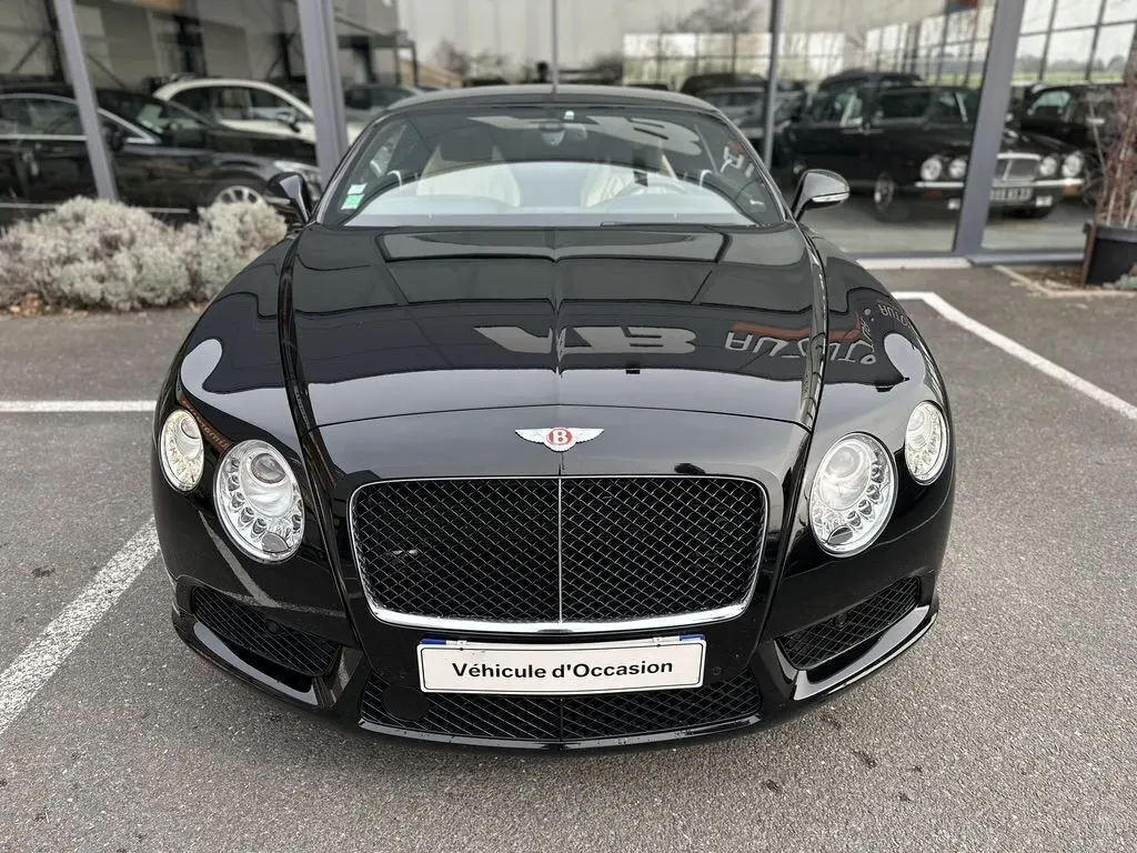 Vue frontale d'une Bentley Continental GT 4.0 V8 Mulliner noire brillante avec calandre distinctive et phares ronds.