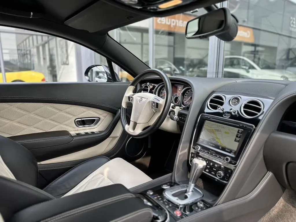 Intérieur beige et noir de la Bentley Continental GT Mulliner 2013, vue côté conducteur avec tableau de bord et console centrale.