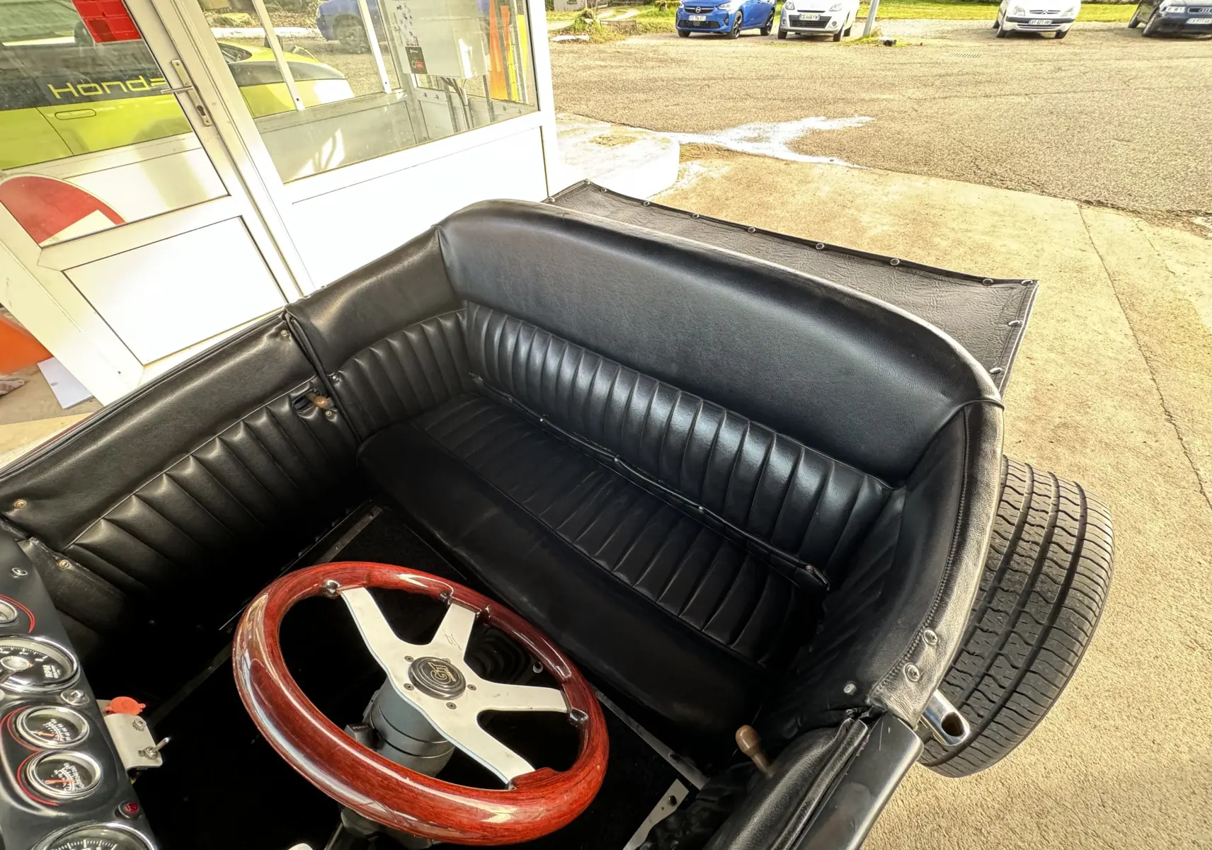 Vue intérieure rapprochée du Ford T Hot Rod 1923 noir, montrant le volant bois et la banquette cuir noire.