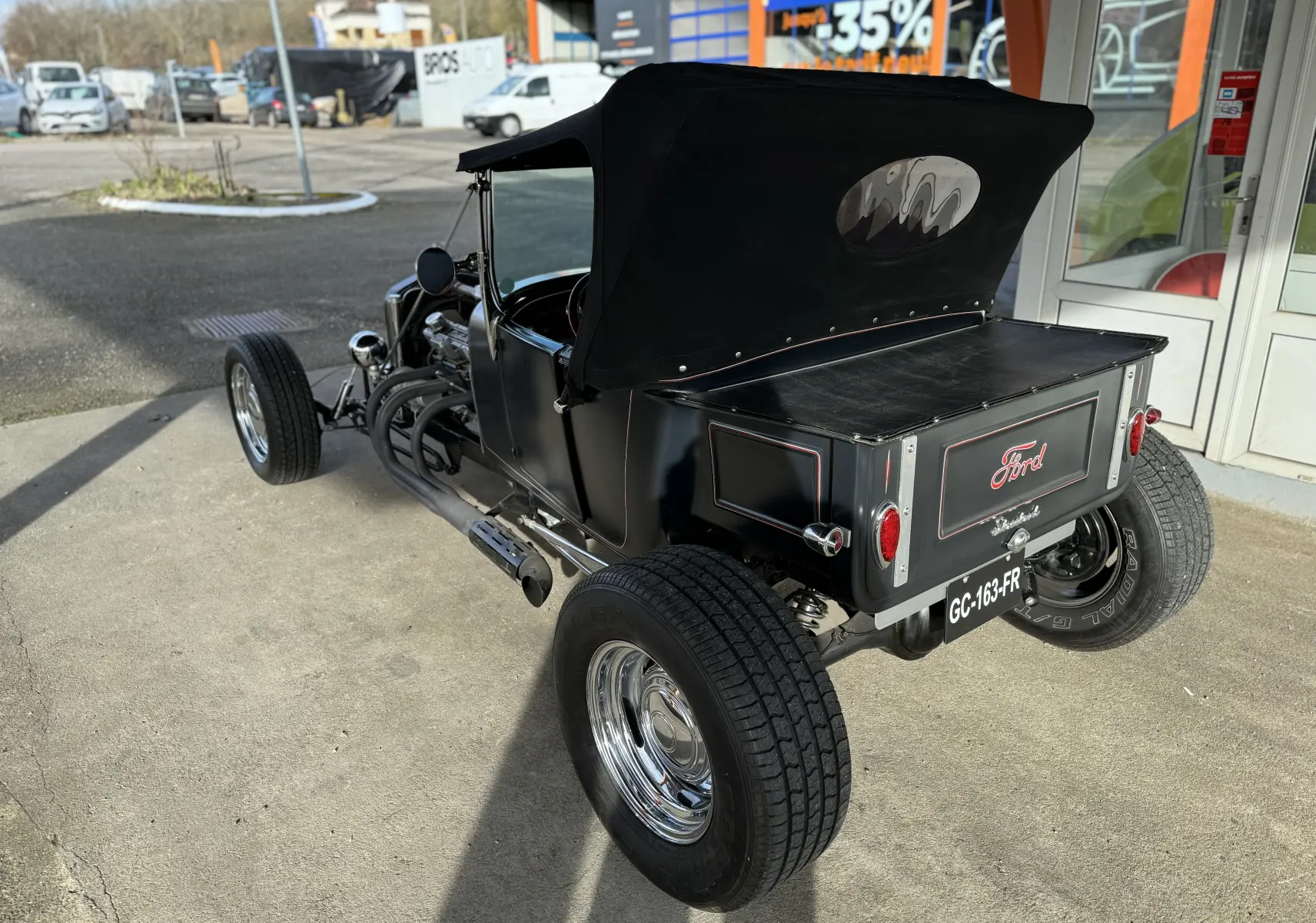 Vue 3/4 arrière droite d'une Ford T Hot Rod V8 noire décapotable avec détails peints à la main et roues chromées.