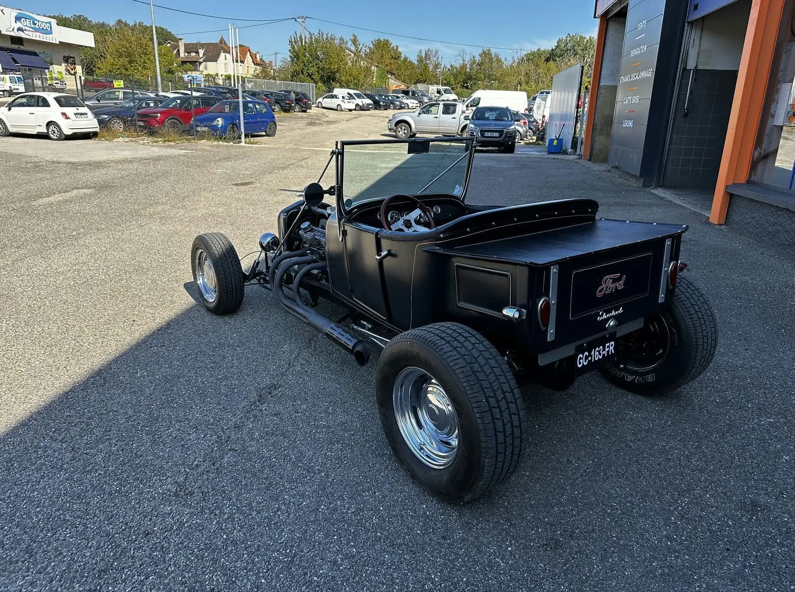 Vue 3/4 arrière droite d'une Ford T Hot Rod V8 noire décapotable avec jantes chromées et coffre plat.