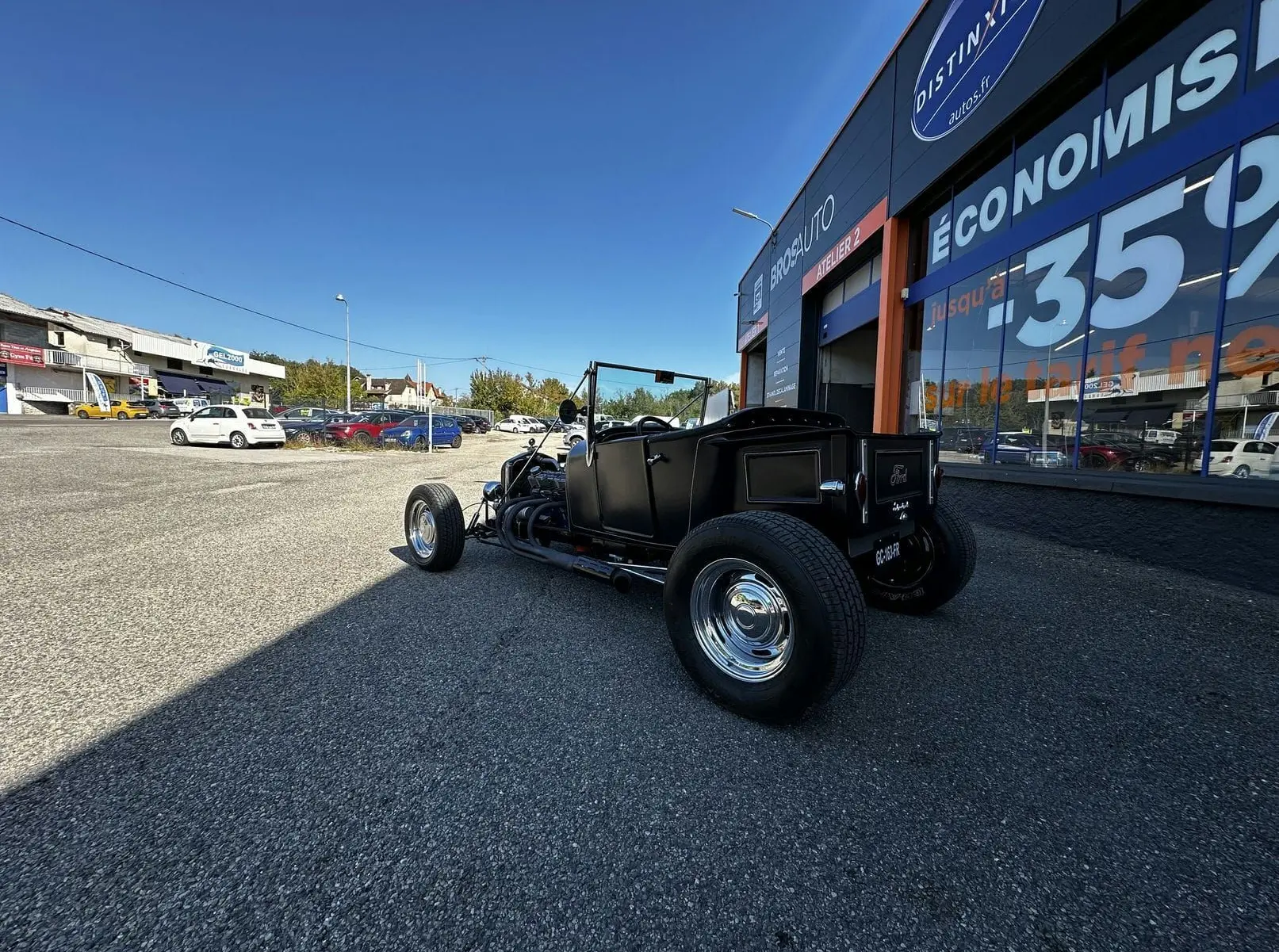 Ford T Hot Rod V8 noir vue 3/4 arrière droit, décapotable avec jantes chromées et moteur apparent.