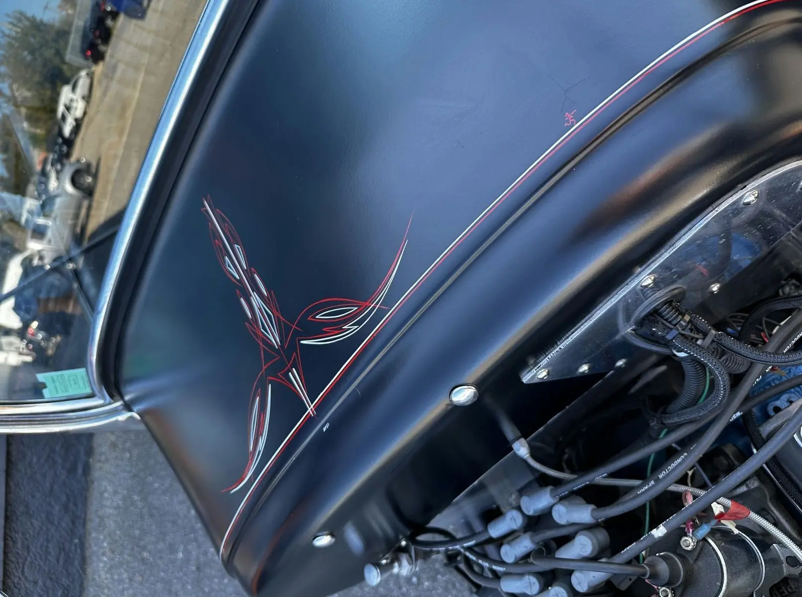 Vue rapprochée du capot noir mat du Ford T Hot Rod 1923 avec motifs rouges et détails du moteur V8 visible.