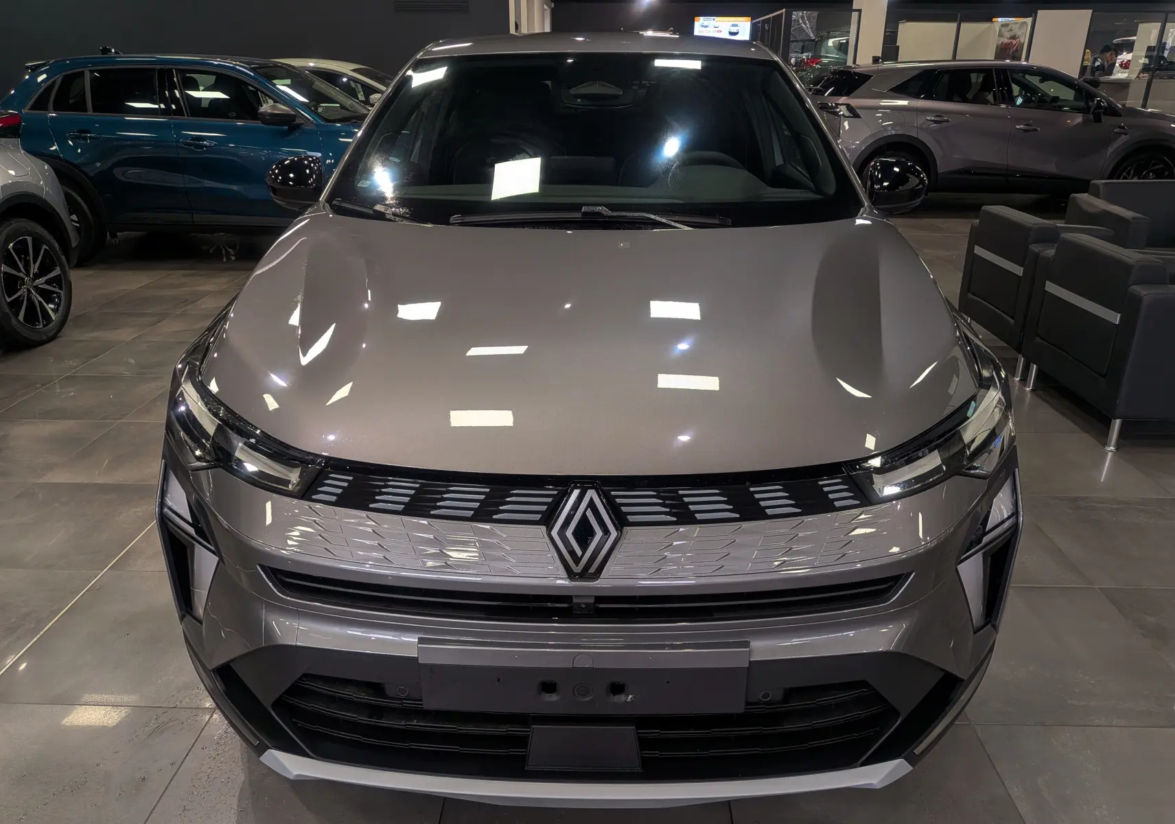 Vue frontale d'une Renault SYMBIOZ E-Tech full hybrid gris Cassiopé, soulignant sa calandre moderne et ses phares fins.