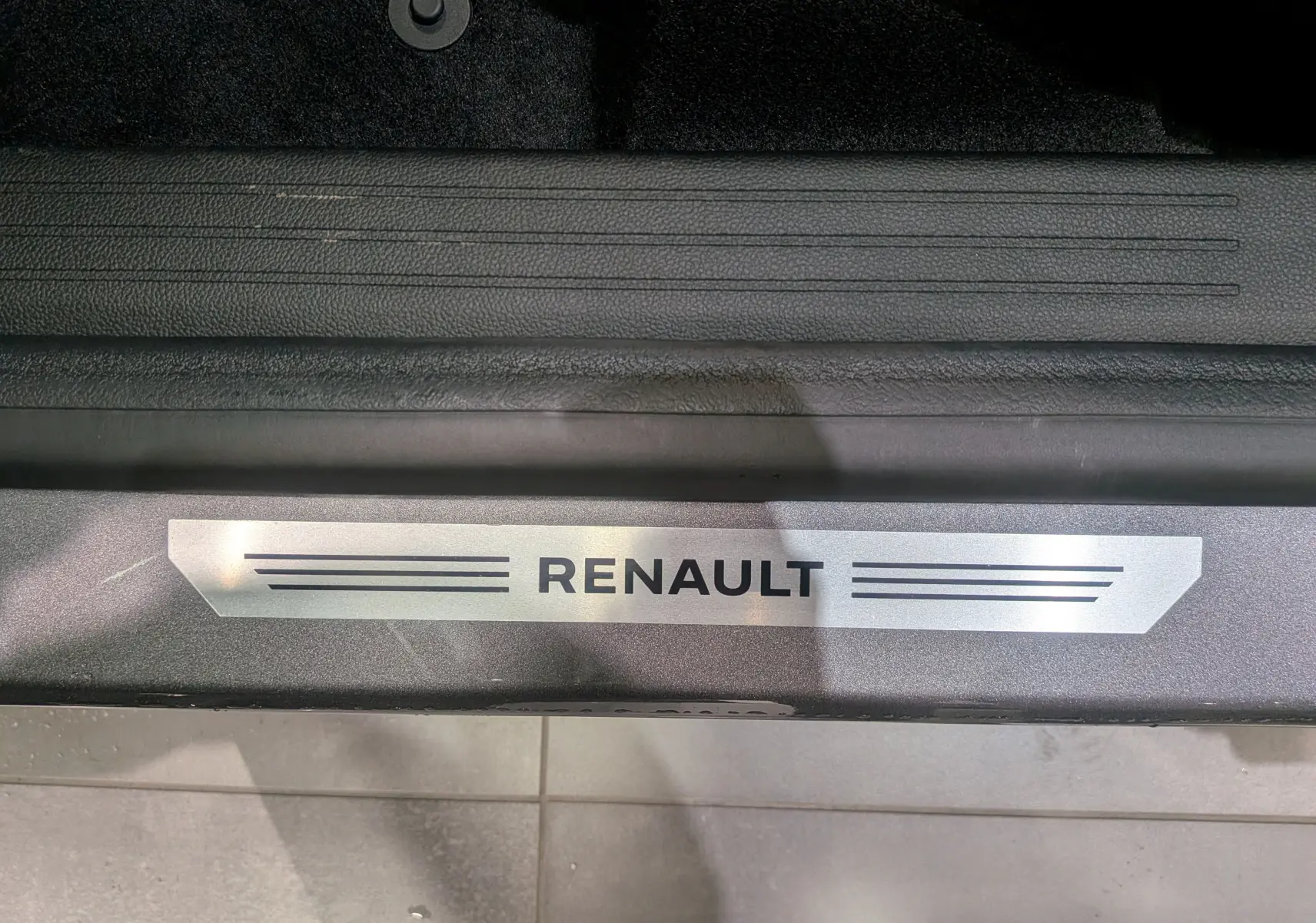 Plaque de seuil de porte avec le logo Renault sur un Renault SYMBIOZ gris Cassiopé, vue en gros plan intérieur.