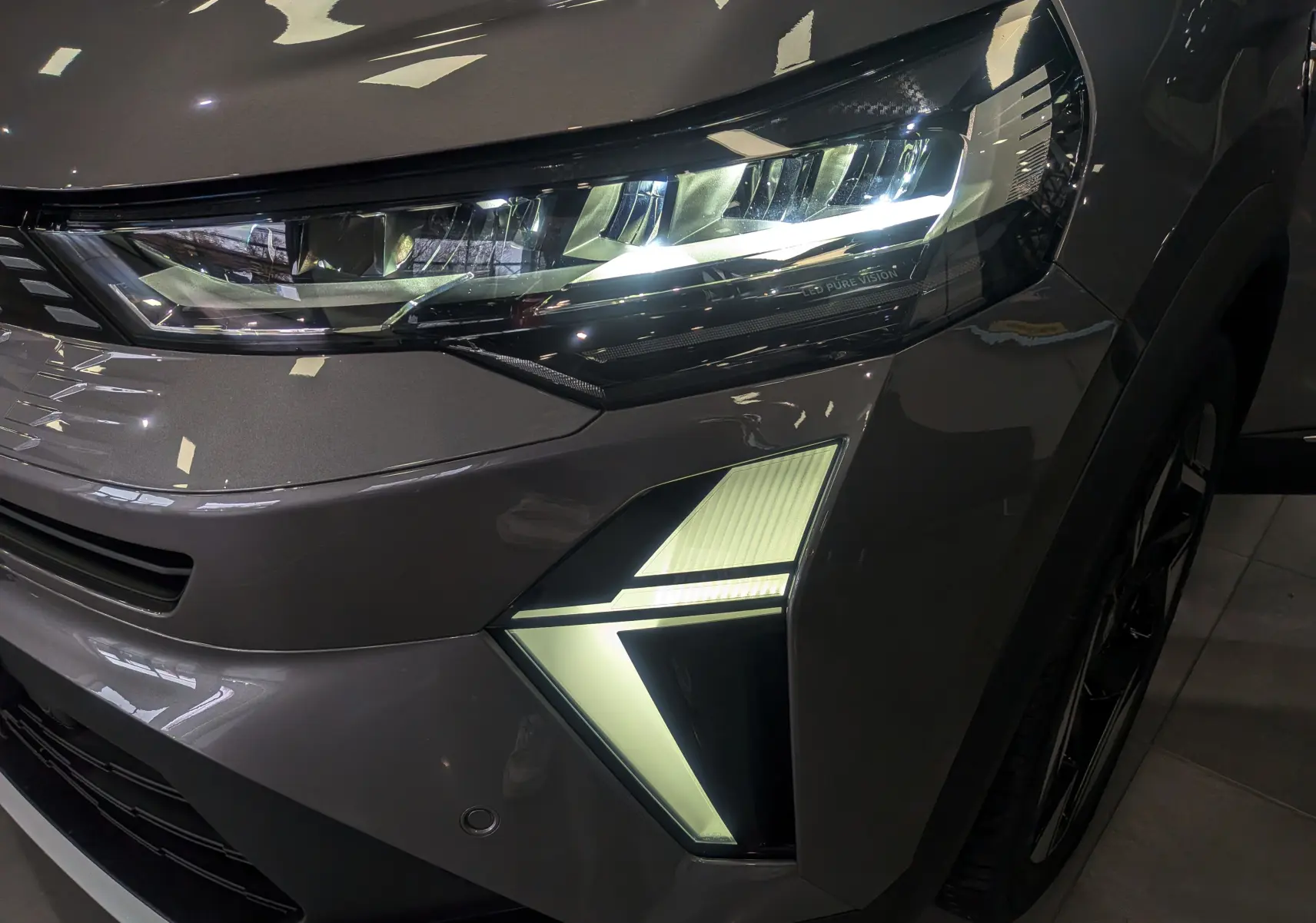 Gros plan sur le phare avant droit allumé du Renault SYMBIOZ gris Cassiopé avec éclairage LED distinctif.