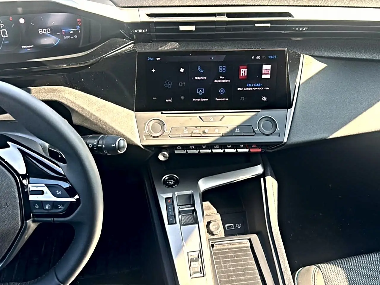 Vue intérieure de la Peugeot 308 2025, tableau de bord et console centrale avec écran tactile et volant multifonction.