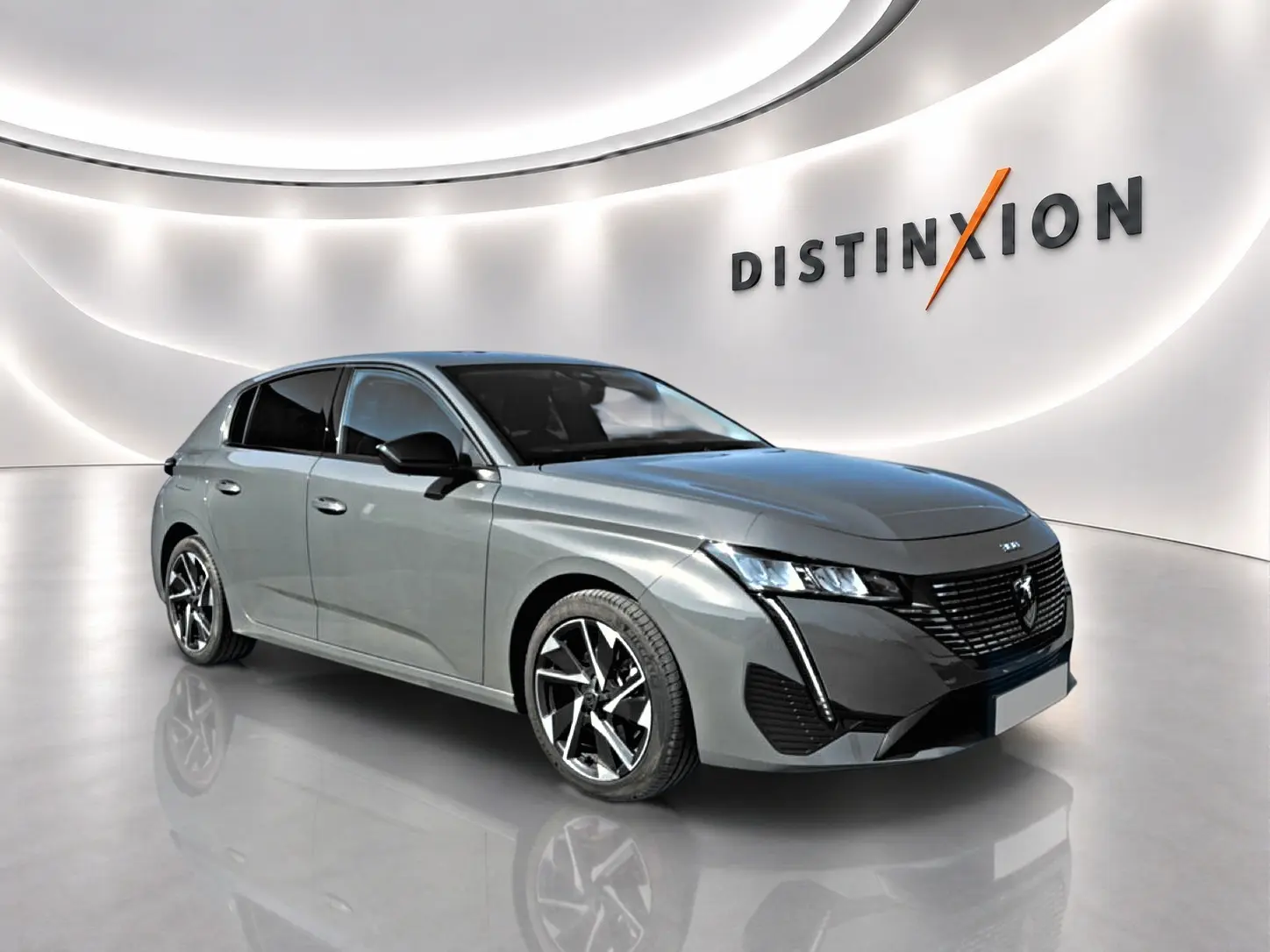 Peugeot 308 gris selenium vue 3/4 avant dans un showroom avec jantes alliage et calandre noire distinctive.