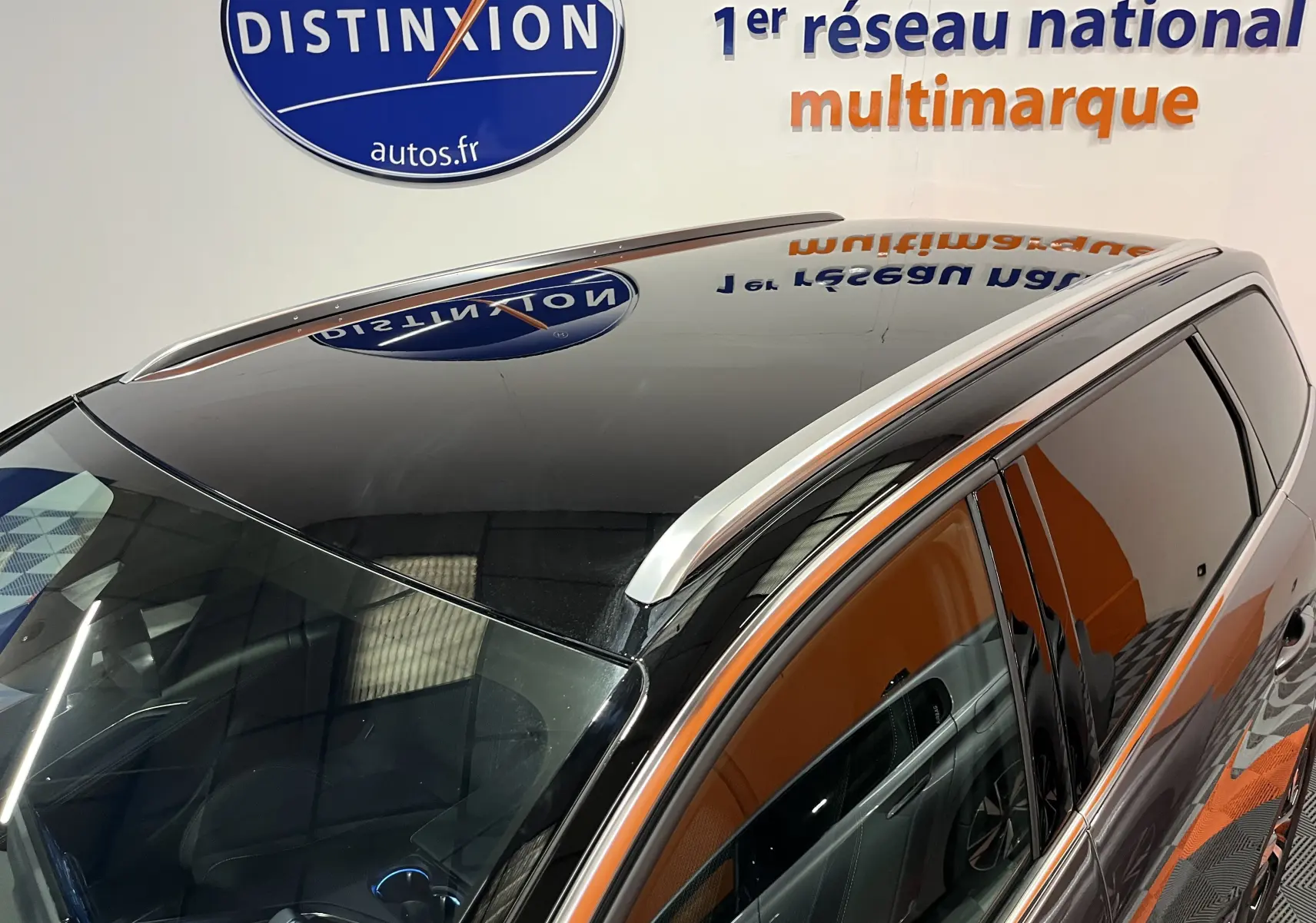 Toit panoramique et barres de toit en aluminium sur le côté gauche d'un Peugeot 5008 gris platinium 2024 en intérieur showroom.