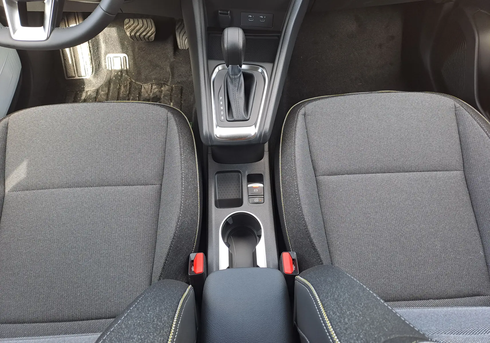 Vue plongeante sur les sièges avant gris tissu et la console centrale avec levier de vitesse automatique du Renault Captur 2025.