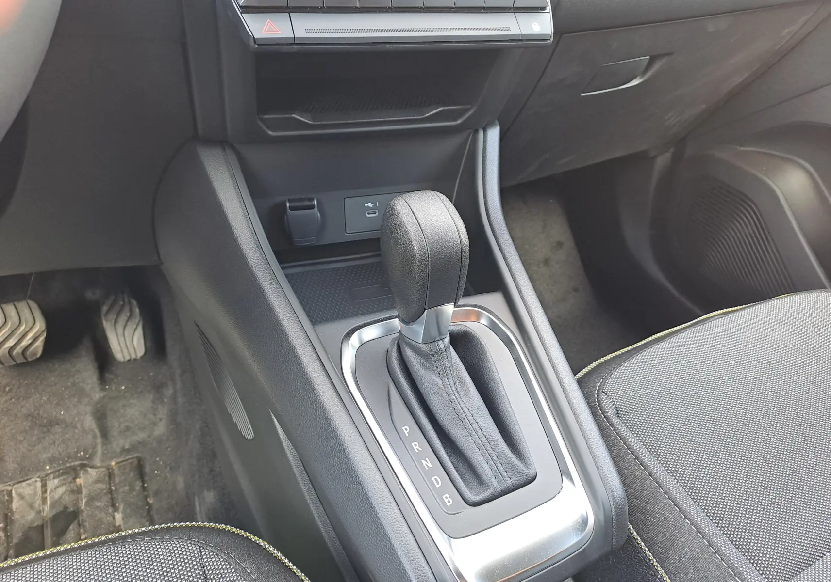 Le levier de vitesses automatique noir du Renault Captur 2025 vu de dessus, avec console centrale et siège gris.