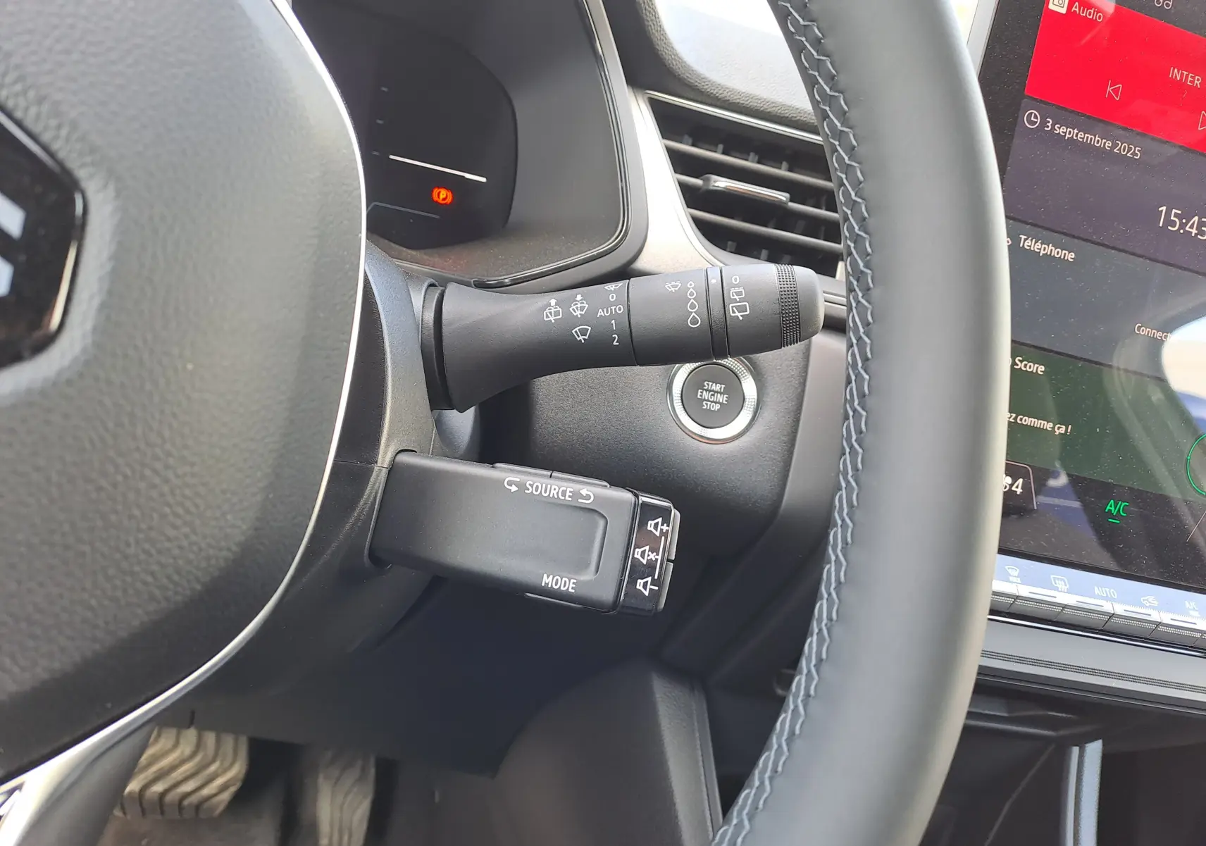 Vue rapprochée du volant et des commandes du tableau de bord du Renault Captur gris Rafale 2025 avec bouton start/stop.